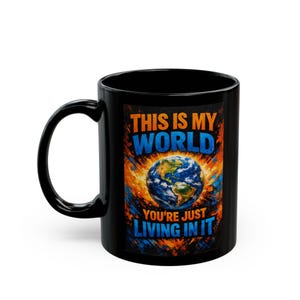 May include: Black ceramic mug featuring a colorful graphic of Earth surrounded by an orange and yellow burst. The text on the mug reads "THIS IS MY WORLD YOU'RE JUST LIVING IN IT" in blue and orange.