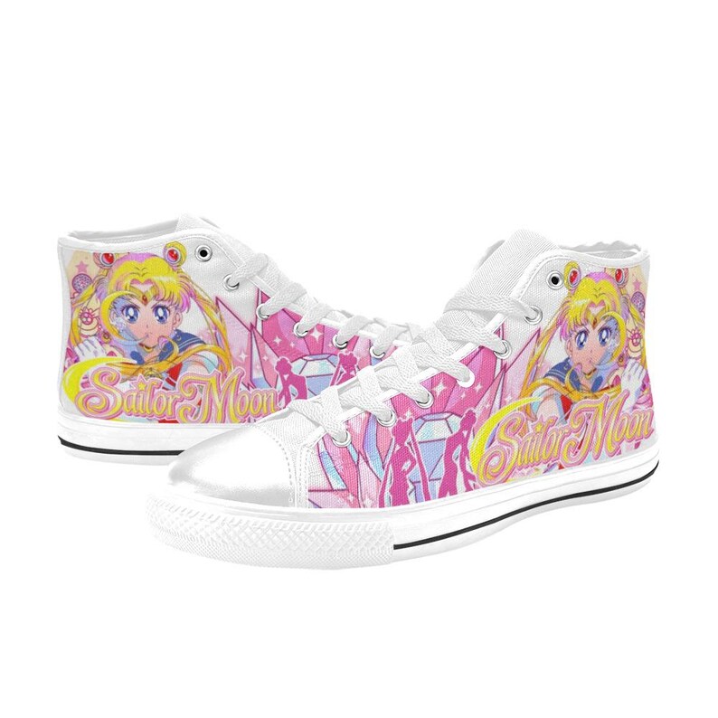 Pu&ograve; includere: Sneakers alte bianche con una grafica colorata di Sailor Moon. Le scarpe hanno una suola e lacci in gomma bianchi, con un design rosa e giallo. Le parole "Sailor Moon" sono stampate sul lato.