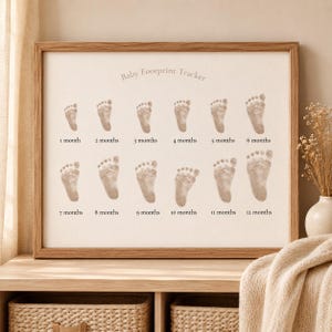 Peut inclure: Un cadre avec l'inscription "Baby Footprint Tracker" et douze empreintes de pas de bébé, chacune numérotée de 1 à 12 mois. Les empreintes de couleur marron clair se détachent sur un fond crème, dans un cadre en bois.