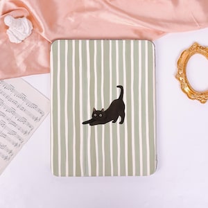 May include: A tablet case featuring a green and white striped design. A black cat illustration is on the front, in a stretching pose. The case is rectangular and has a smooth finish.