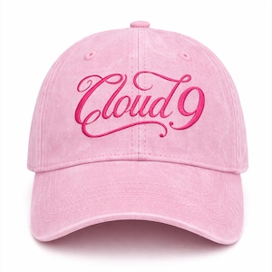 May include: A light pink baseball cap with the embroidered text "Cloud 9" in a darker pink script. The cap has a curved brim and a rounded top, and is made of a soft, textured fabric.
