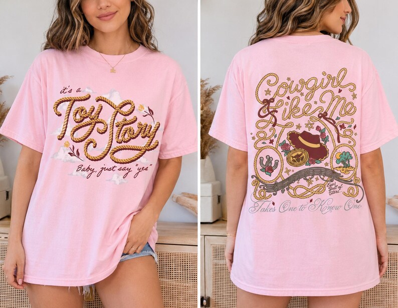 Op de afbeelding: Een lichtroze t-shirt met een voorzijde voorzien van touwachtige tekst "it's a Toy Story Baby, just say 'yes'" en een achterzijde met touwranden, een cowboyhoed en de tekst "Cowgirl like Me" en "Takes One to Know One."