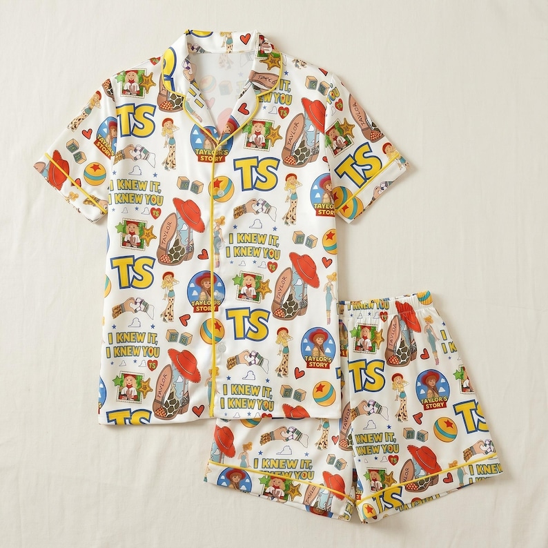 May include: A white short-sleeve button-down pajama shirt and matching shorts set featuring a colorful repeating print of cowboy boots, red hats, yellow TS text, and the phrase I KNEW IT, I KNEW YOU with yellow piping along the edges.