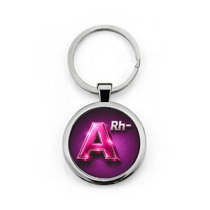 May include: A circular, silver keyring with a purple background. The keyring features a metallic pink letter "A" with "Rh-" in white text. The keyring is a blood type accessory.