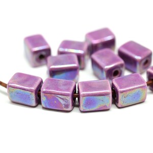 May include: A strand of iridescent purple ceramic square beads. The beads have a glossy finish and are strung on a brown cord.