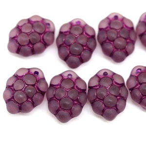 Könnte beinhalten: Acht violette Glasperlen mit einem strukturierten, wabenförmigen Design. Die Perlen haben eine matte Oberfläche und sind perfekt für die Schmuckherstellung.
