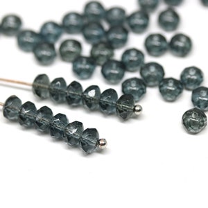 May include: A strand of dark blue faceted glass beads, strung on a silver wire. The beads are round and have a faceted finish.