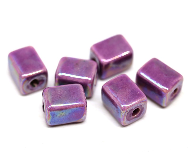 May include: Six iridescent purple square ceramic beads with a hole in the center.