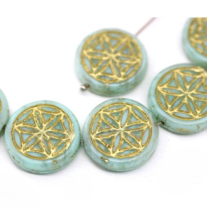 May include: A strand of round, turquoise-colored glass beads with a gold geometric design. The beads are strung on a wire.