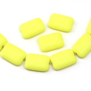 Può includere: Una collana di perline rettangolari in vetro giallo. Le perline sono opache e hanno una superficie leggermente ruvida.