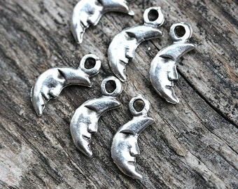 May include: Six silver crescent moon charms with a face on each moon. The charms have a loop at the top for attaching to jewelry or other crafts.