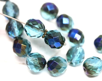 May include: A strand of faceted glass beads in shades of teal and blue. The beads are strung on a silver wire and have a iridescent finish.