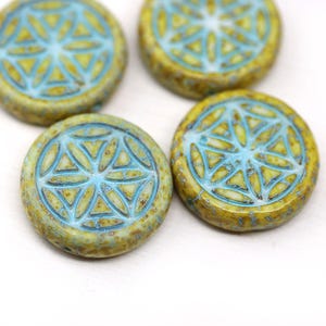 May include: Four round, flat beads with a light blue geometric design on a yellow-green background. The beads have a slightly textured appearance and are arranged against a white background.