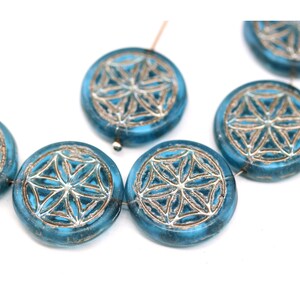May include: A strand of turquoise blue glass beads with a silver metallic flower design. The beads are round and have a slightly textured surface.