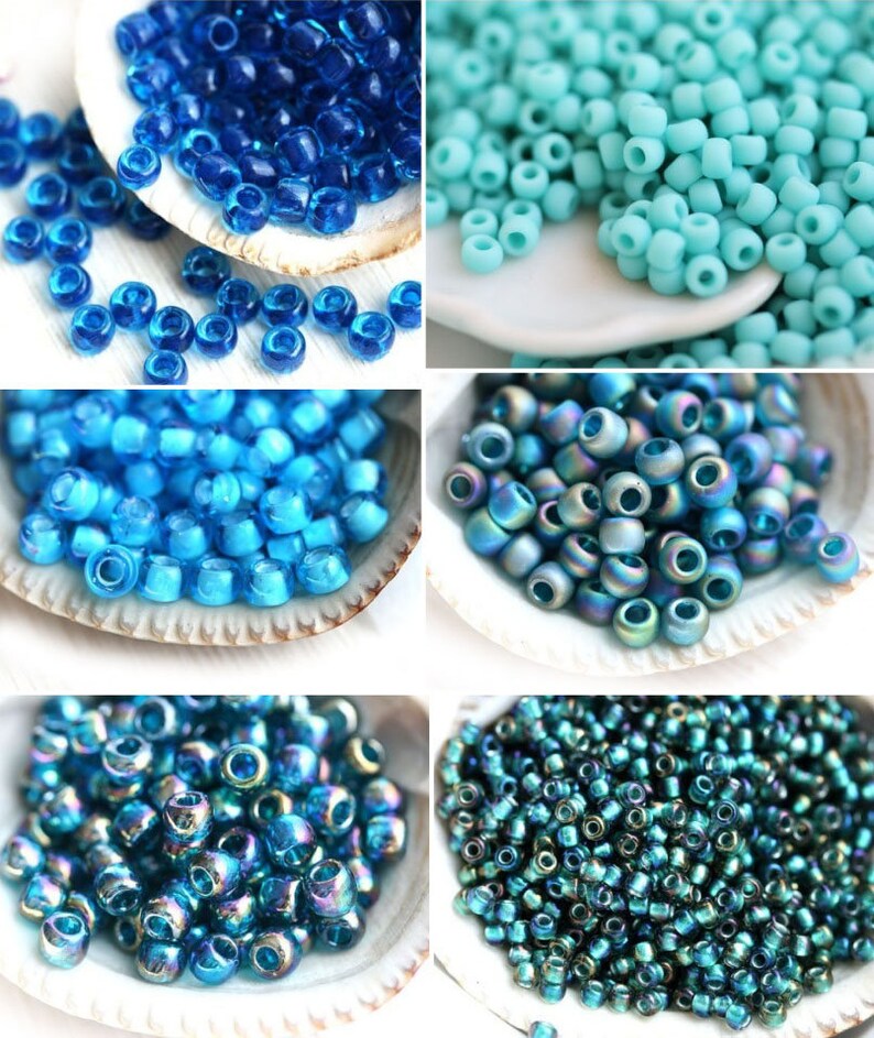 Op de afbeelding: Assortiment van blauwe glazen kralen in verschillende tinten en afwerkingen, waaronder helder, iriserend en ondoorzichtig. De kralen worden gepresenteerd in kleine witte kommen.