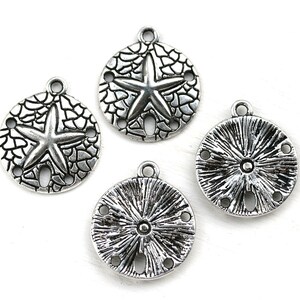 May include: Four silver-toned metal charms shaped like sand dollars. Two charms feature a starfish design, and two charms feature a sunburst design.