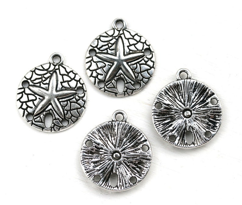 May include: Four silver-toned metal charms shaped like sand dollars. Two charms feature a starfish design, and two charms feature a sunburst design.