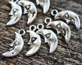May include: A collection of silver-toned crescent moon charms with a face on each. The charms have a loop at the top for attaching to jewelry or other crafts.