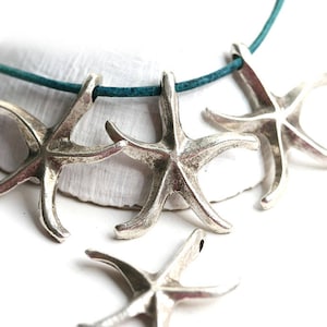 May include: Silver starfish necklace with a teal blue cord. The necklace features three starfish charms.