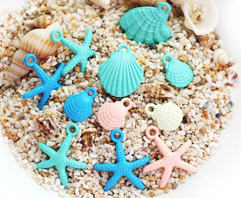 May include: Assortment of colorful seashell charms in various shapes, including starfish, seashells, and clams. The charms are made of metal and have a shiny finish. They are perfect for adding a touch of beachy style to jewelry, crafts, and other projects.
