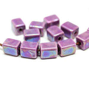 May include: A strand of iridescent purple ceramic square beads. The beads have a glossy finish and are strung on a brown cord.