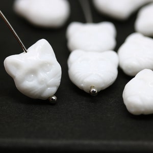 May include: White ceramic cat head beads with a detailed face and a hole for stringing.