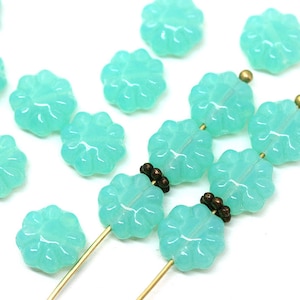 May include: A strand of turquoise blue glass beads in the shape of flowers. The beads are strung on a gold wire.