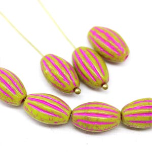 Puede incluir: Primer plano de varias cuentas ovaladas de color verde oliva con rayas rosas brillantes. Cada cuenta tiene un pequeño extremo de metal dorado. Las cuentas están ensartadas en un alambre fino de color dorado. Las cuentas son para hacer joyas.