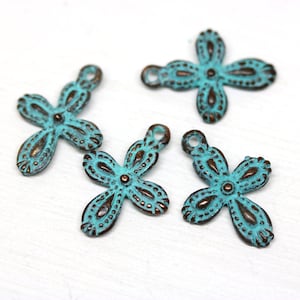 May include: Four turquoise blue metal flower charms with a distressed finish. Each charm has a loop for attaching to jewelry or other crafts.