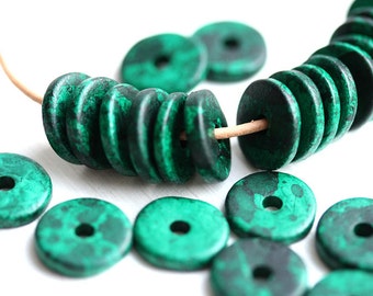 May include: A strand of green wooden beads with a marbled effect. The beads are round and have a hole in the center. There are several loose beads scattered around the strand.