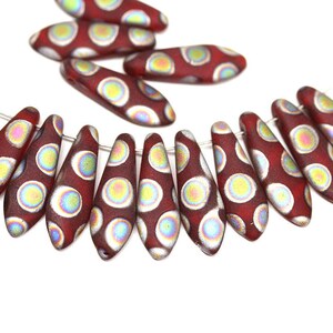 May include: A strand of red glass beads with iridescent white polka dots. The beads are shaped like teardrops and are strung on a silver wire.