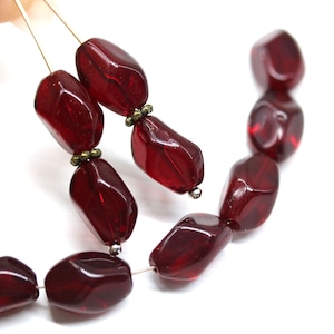 Peut inclure: Un brin de perles de verre facettées rouge foncé avec des accents argentés et dorés. Les perles sont enfilées sur un fil fin.