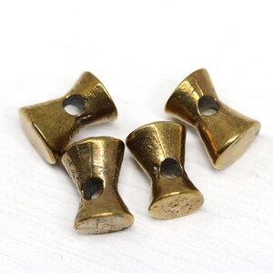 May include: Four gold-toned metal toggle buttons with a hole in the center of each. The buttons are shaped like an hourglass.