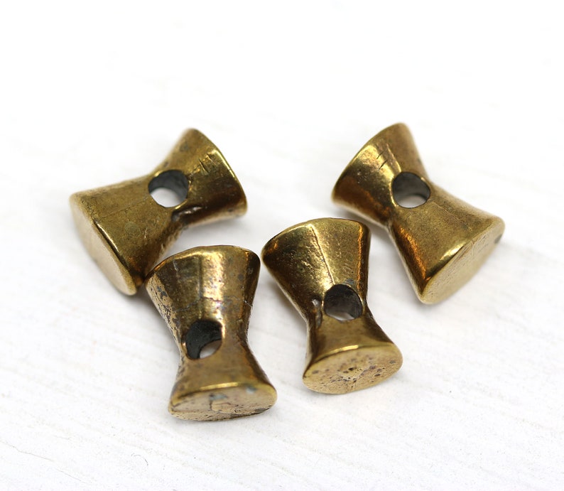 May include: Four gold-toned metal toggle buttons with a hole in the center of each. The buttons are shaped like an hourglass.
