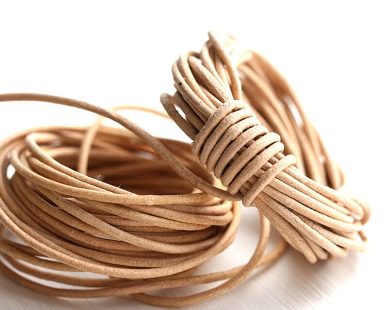 May include: A close-up of a coil of natural-colored leather cord. The cord is soft and supple, and it is perfect for crafting jewelry, accessories, and other projects.