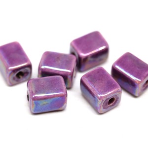 May include: Six iridescent purple square ceramic beads with a hole in the center.