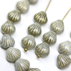 May include: A strand of gray glass beads with gold accents in the shape of seashells.