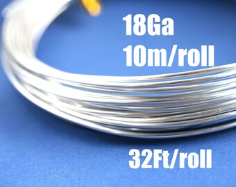 Puede incluir: Primer plano de una bobina de alambre plateado sobre un fondo azul. El alambre es de calibre 18 y viene en un rollo de 10 metros, lo que equivale a 32 pies.