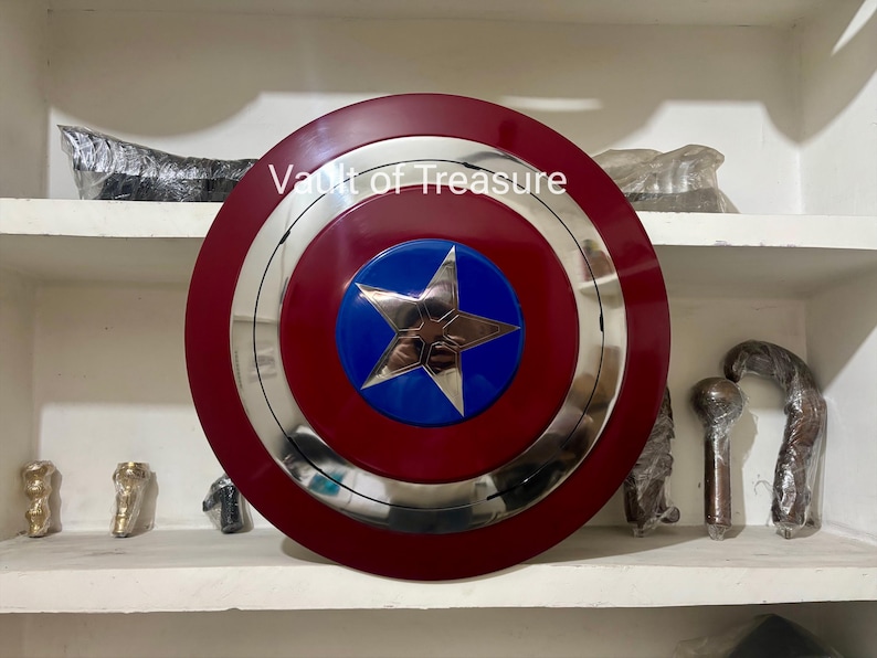 May include: A Captain America shield replica. The shield features a red outer ring, a silver inner ring, and a blue center with a silver star. The text "Vault of Treasure" is visible on the shield.