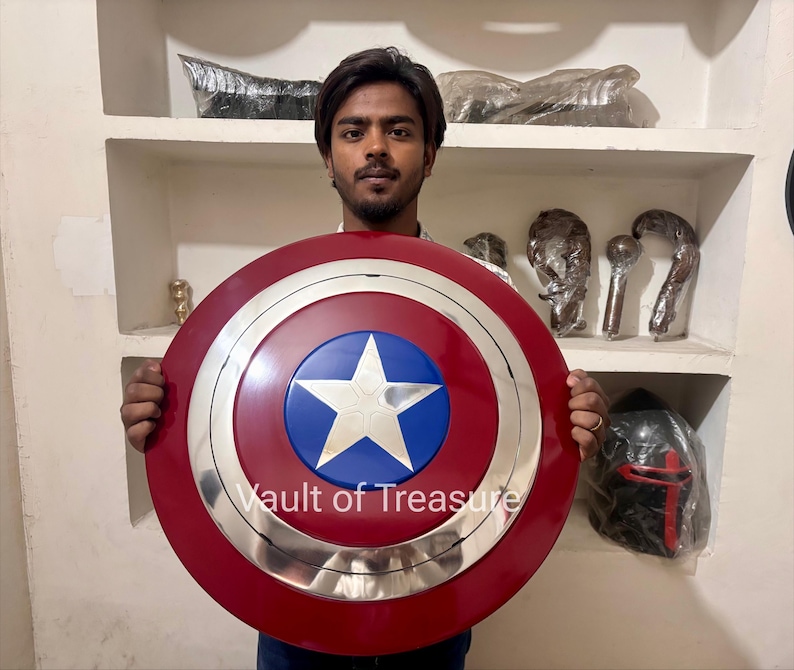 May include: A Captain America shield with a red, white, and blue color scheme. The shield features a white star on a blue circle, surrounded by a silver ring and a red outer ring. The text "Vault of Treasure" is visible.