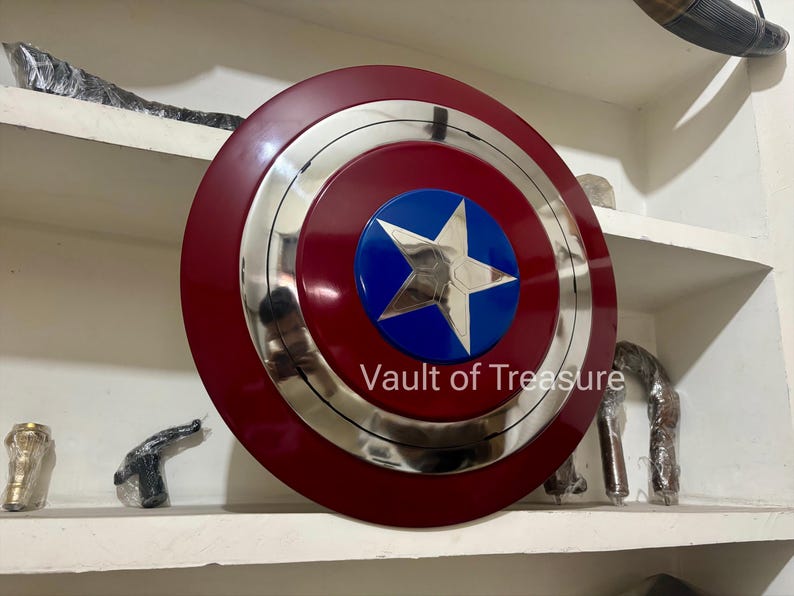 May include: A red, silver, and blue shield with a star emblem. The shield has a circular design with a red outer ring, a silver middle ring, and a blue center with a white star. The text "Vault of Treasure" is visible.