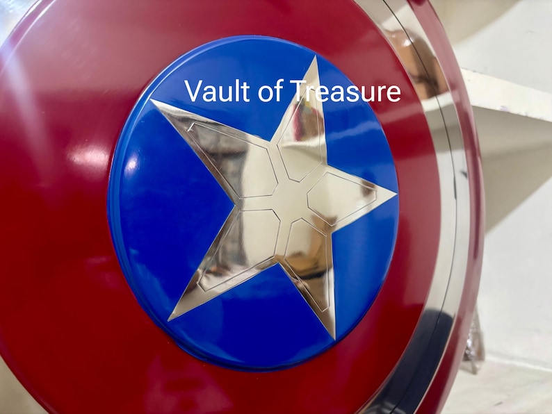 May include: A red, white, and blue shield with a large silver star in the center. The star is set against a blue circle, and the shield has a metallic silver border. The text "Vault of Treasure" is visible on the blue circle.