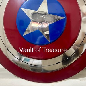May include: A red, white, and blue shield with a silver star in the center. The shield has a circular design with concentric rings and the text "Vault of Treasure" in white.