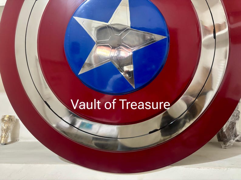 May include: A red, white, and blue shield with a silver star in the center. The shield has a circular design with concentric rings and the text "Vault of Treasure" in white.