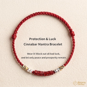 Puede incluir: Pulsera Cinnabar Mantra roja con texto "Protection & Luck". La pulsera presenta un cordón rojo tejido con una serie de cuentas rojas, plateadas y doradas. El texto de la imagen dice: "Wear it! Block out all bad luck, and let only peace and prosperity remain."