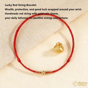 Puede incluir: Una pulsera de hilo rojo con un dije de moneda de oro. La pulsera es hecha a mano y presenta el texto "Lucky Red String Bracelet". El dije es una pequeña moneda de oro con una inscripción.