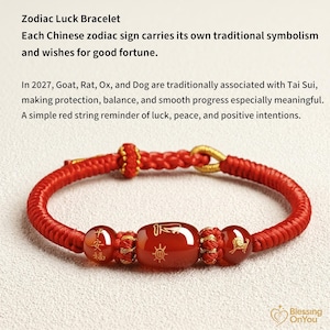 Könnte beinhalten: Ein rotes Schnurarmband mit drei glatten, dunkelorangen Perlen mit goldfarbenen Gravuren. Die mittlere Perle ist oval geformt und wird von zwei kleineren runden Perlen flankiert. Das Armband besteht aus einer geflochtenen roten Schnur mit Verschluss.