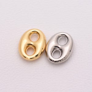 May include: Two shiny, bean-shaped jewelry charms. One is gold-colored, the other is silver-colored. Each charm has two circular holes. These charms are suitable for necklaces, bracelets, or earrings.