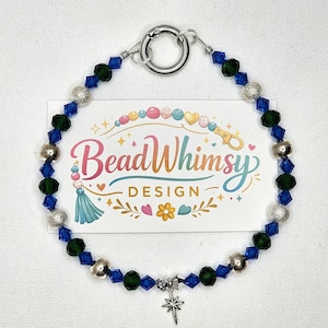 May include: A beaded bracelet featuring alternating blue and green crystal beads, silver-colored beads, and a silver star charm. The bracelet has a silver clasp. A card behind the bracelet reads "Bead Whimsy Design".