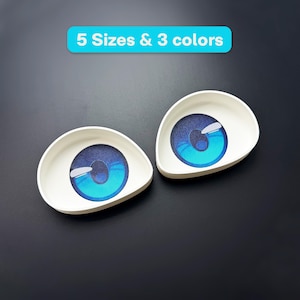 Könnte beinhalten: Zwei weiße, tropfenförmige Augen-Einsätze mit großen, leuchtend blauen Iris, dunklen Pupillen und weißen Glanzlichtern. Über den Augen befindet sich ein hellblaues rechteckiges Banner mit dem weißen Text 5 Sizes & 3 colors.
